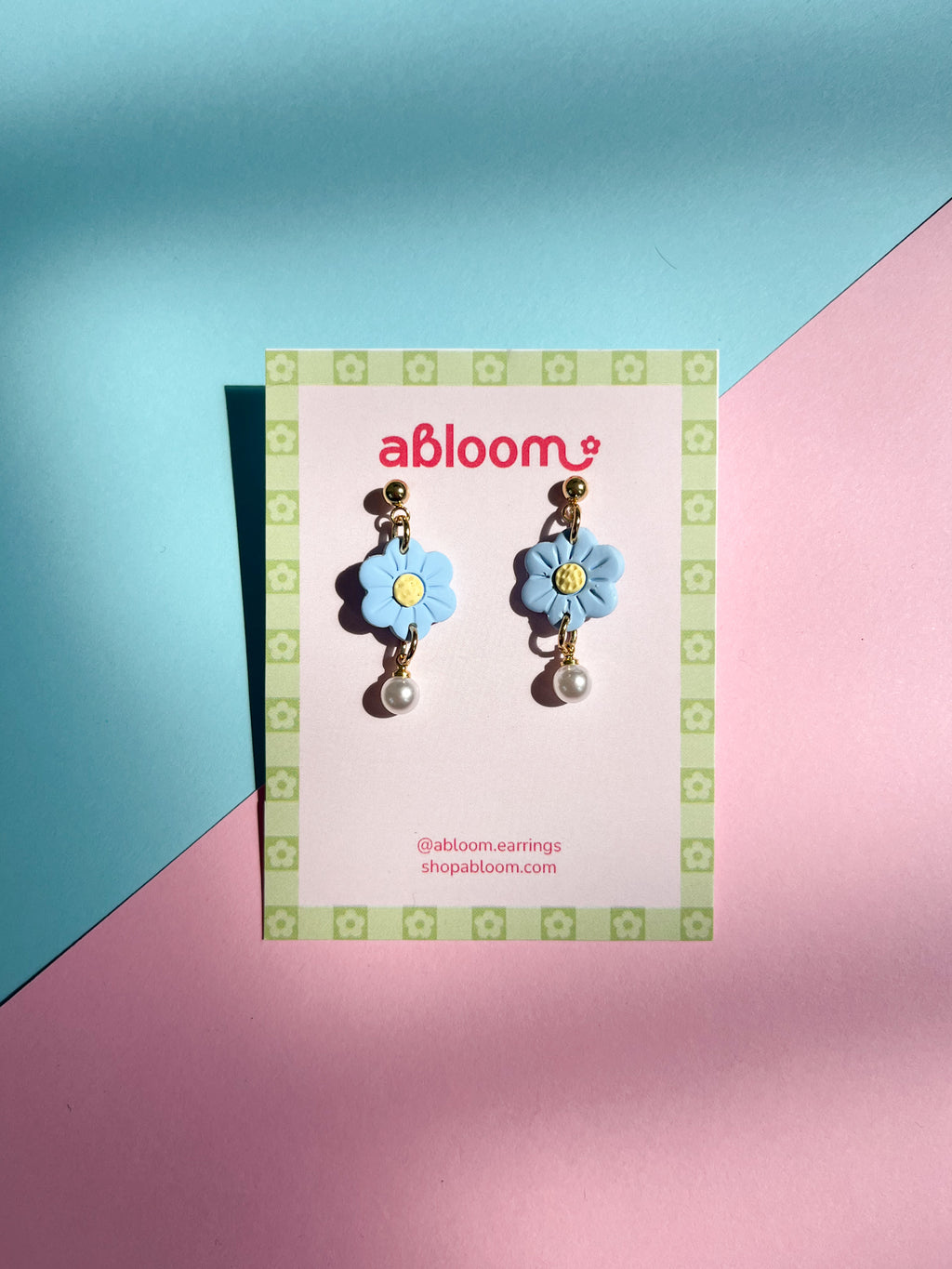 Flower-shaped earrings on a 'abloom' branded card against a colorful background