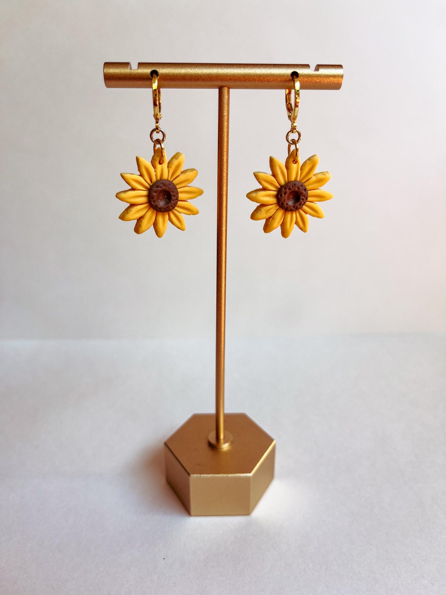 yellow sunflower earrings hanging on a earring display