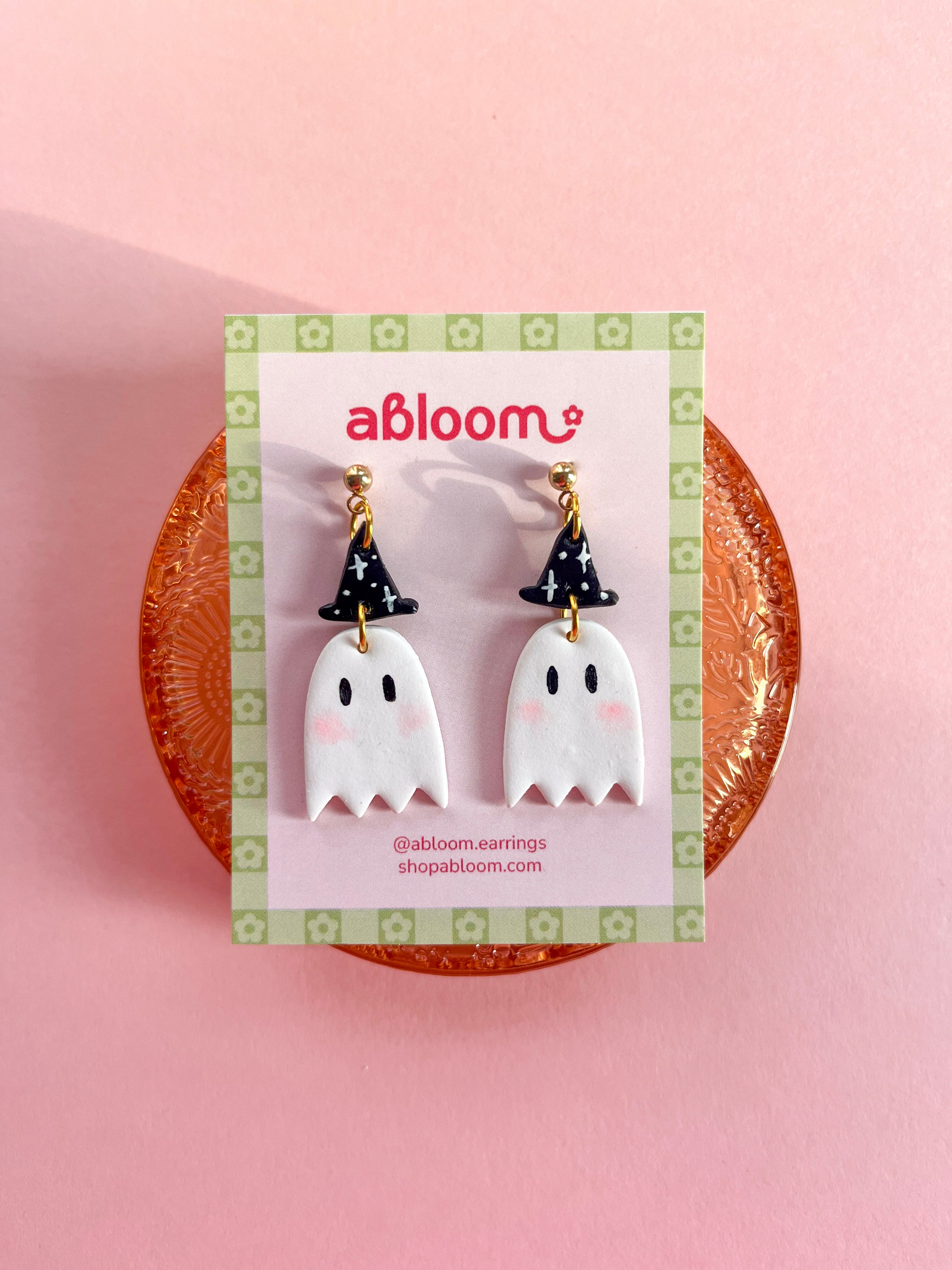 A pair of cute ghost drop earrings with black witch hats.