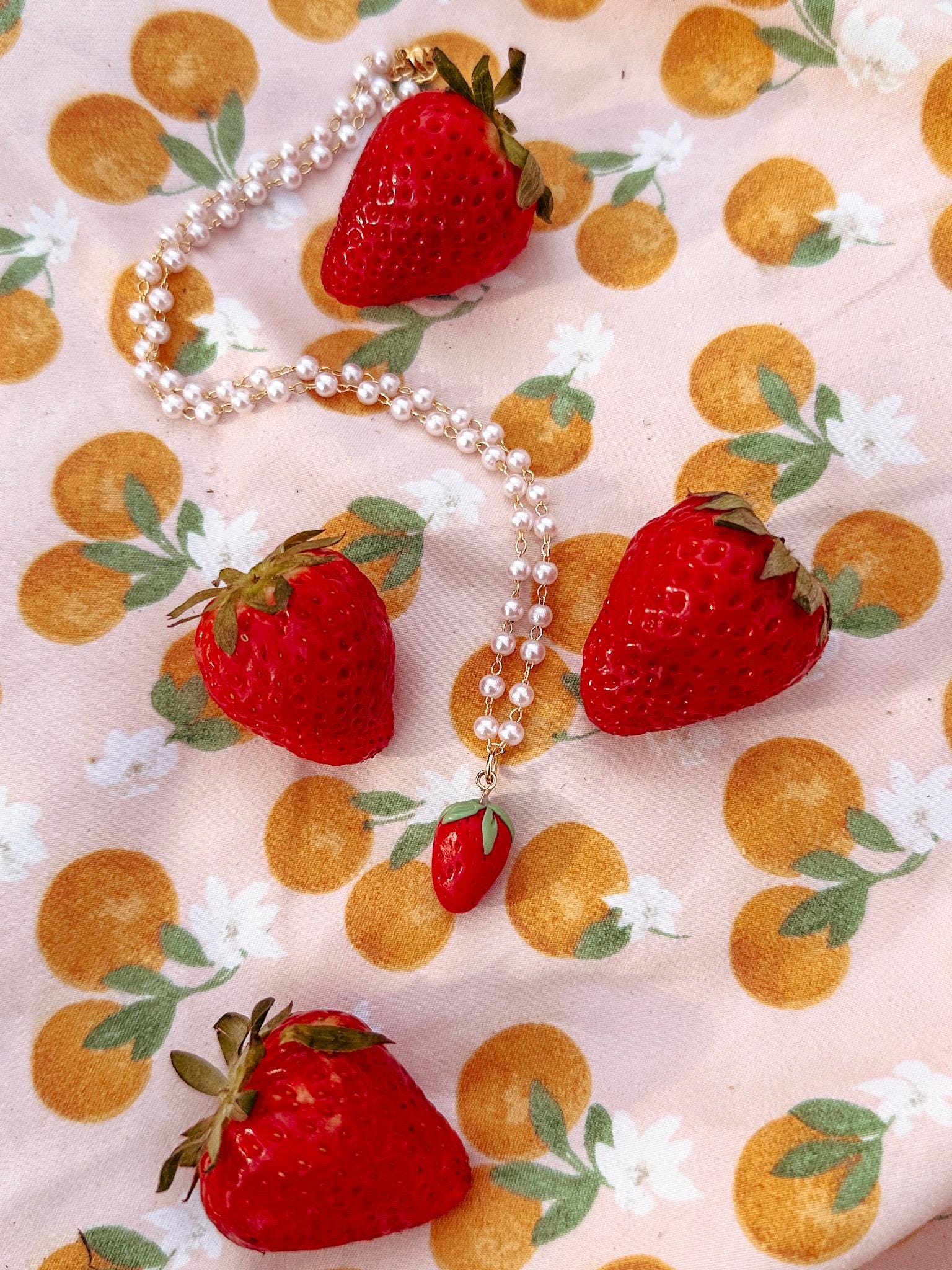 Pearl necklace with strawberries on a patterned fabric background
