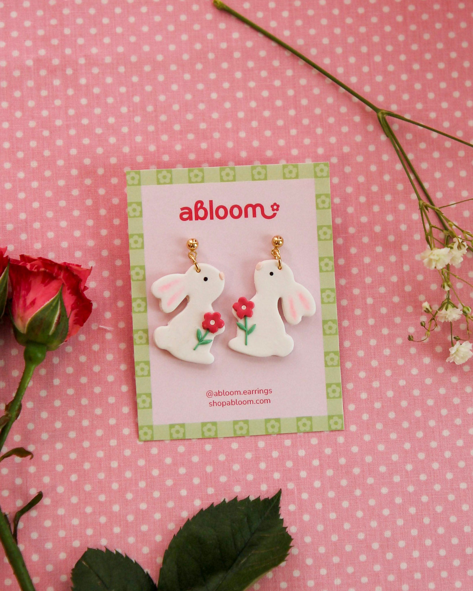 white bunny earrings holding a pink flower