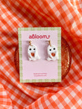 Cute handmade ghost earrings holding tiny pumpkins with whimsical Halloween design
