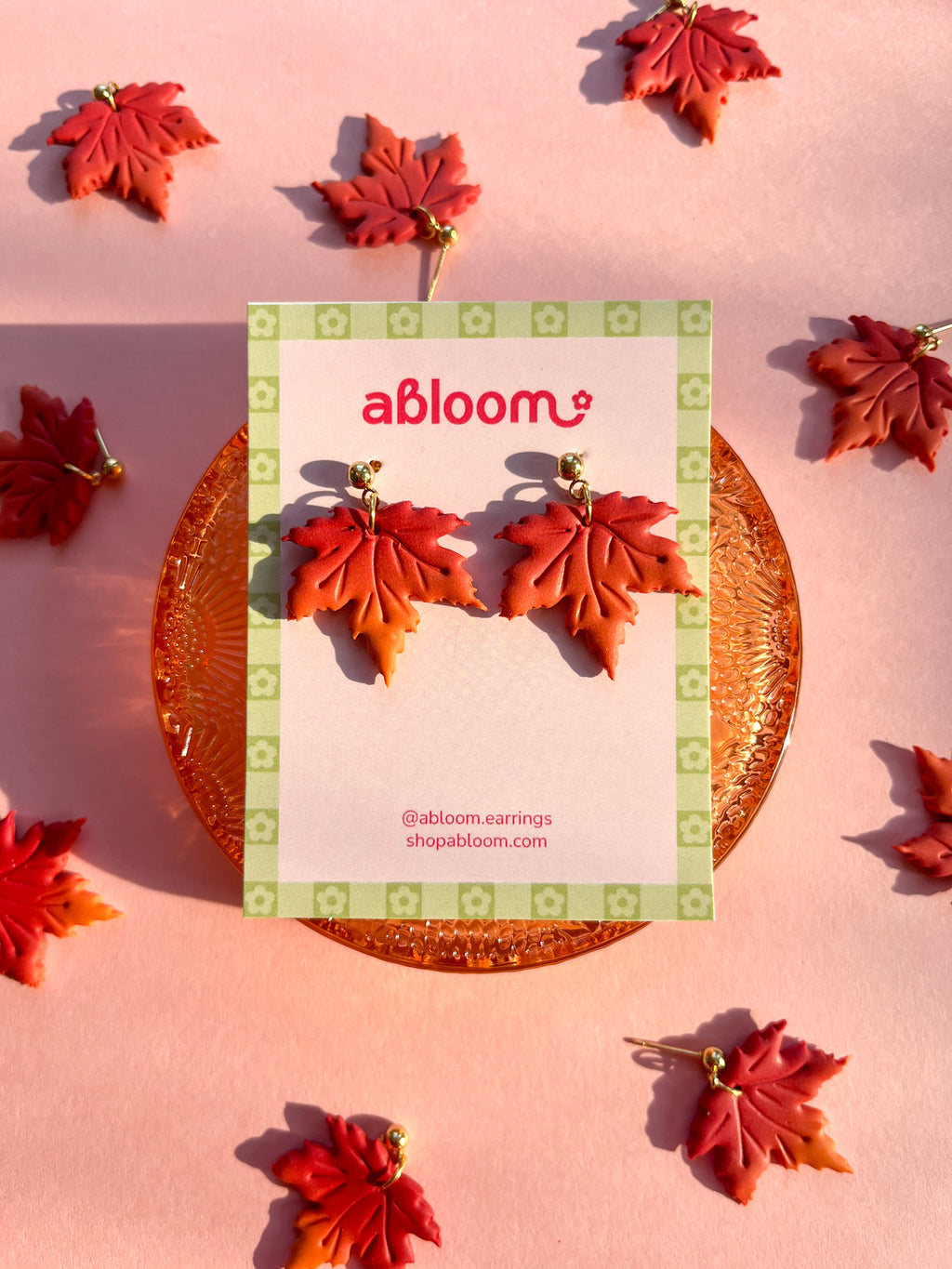 Maple Leaf-shaped dangle earrings in shades of red and orange.