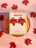 Maple Leaf-shaped dangle earrings in shades of red and orange.