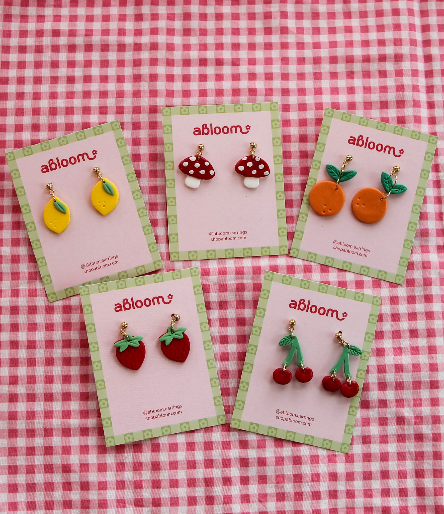 Set of 'abloom' earrings on display with a red and white checkered background