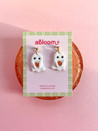 Cute handmade ghost earrings holding tiny pumpkins with whimsical Halloween design