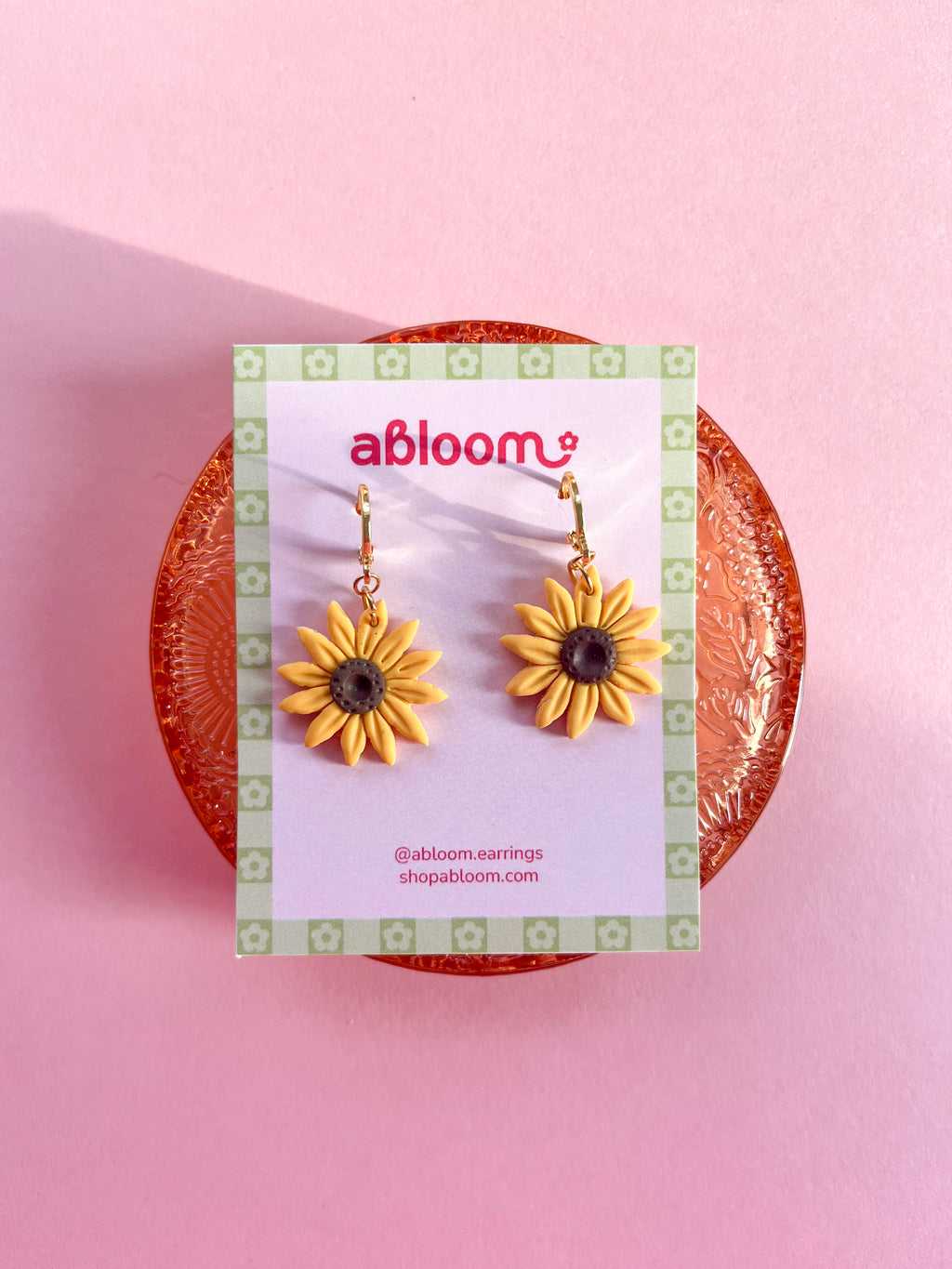 yellow sunflower dangle earrings displayed on an earring card