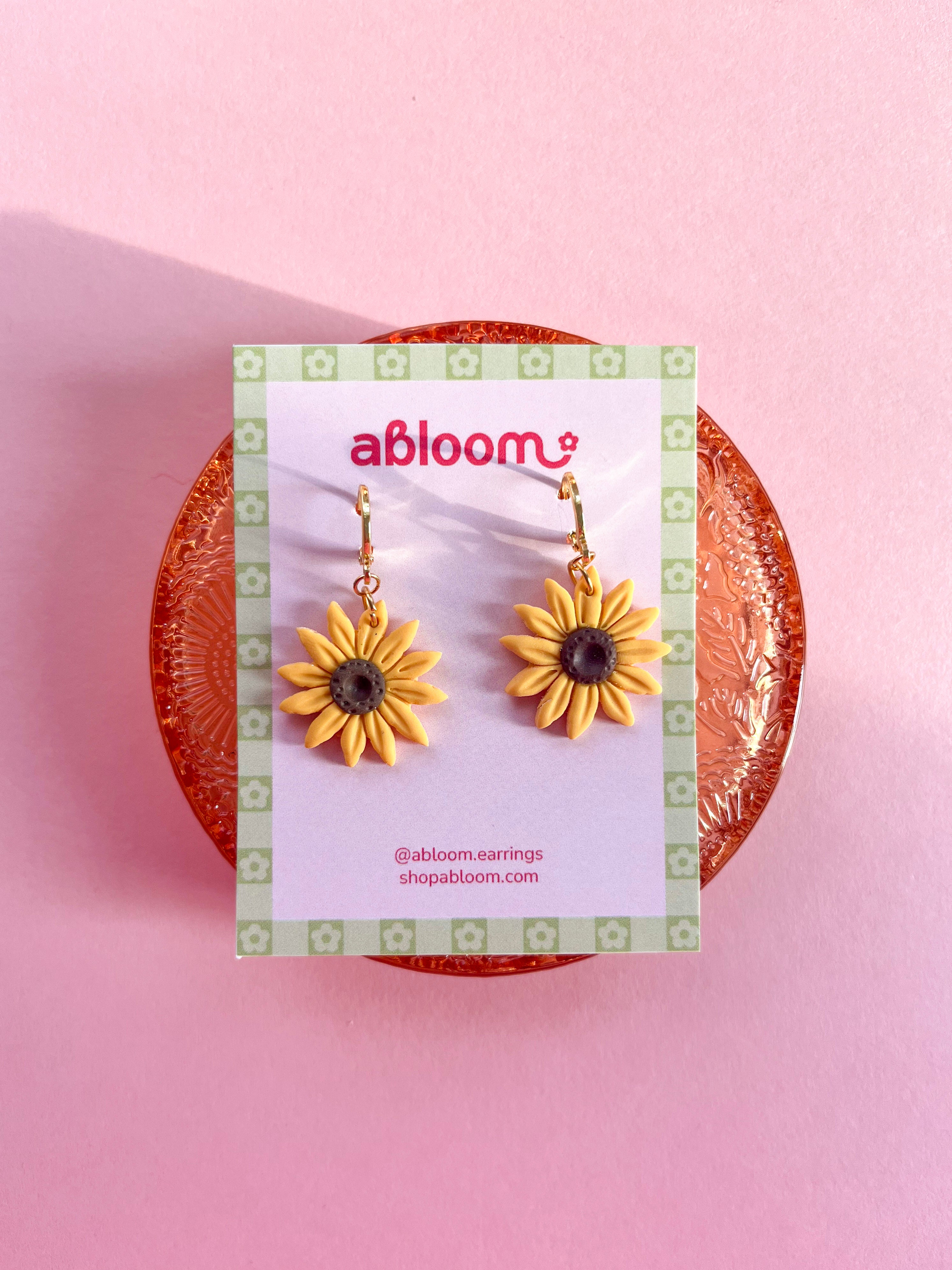 yellow sunflower dangle earrings displayed on an earring card
