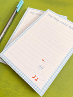 Two notepads with a goose illustration and text on a green background