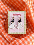 A pair of white cat ghost earrings wearing a witch hat 