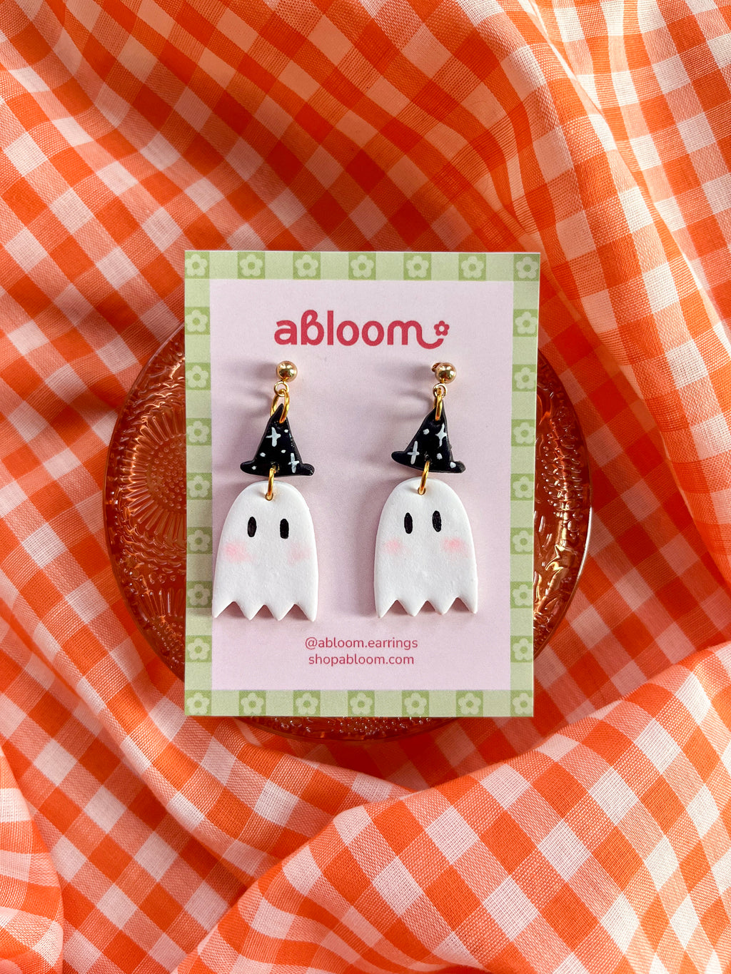 A pair of cute ghost drop earrings with black witch hats.