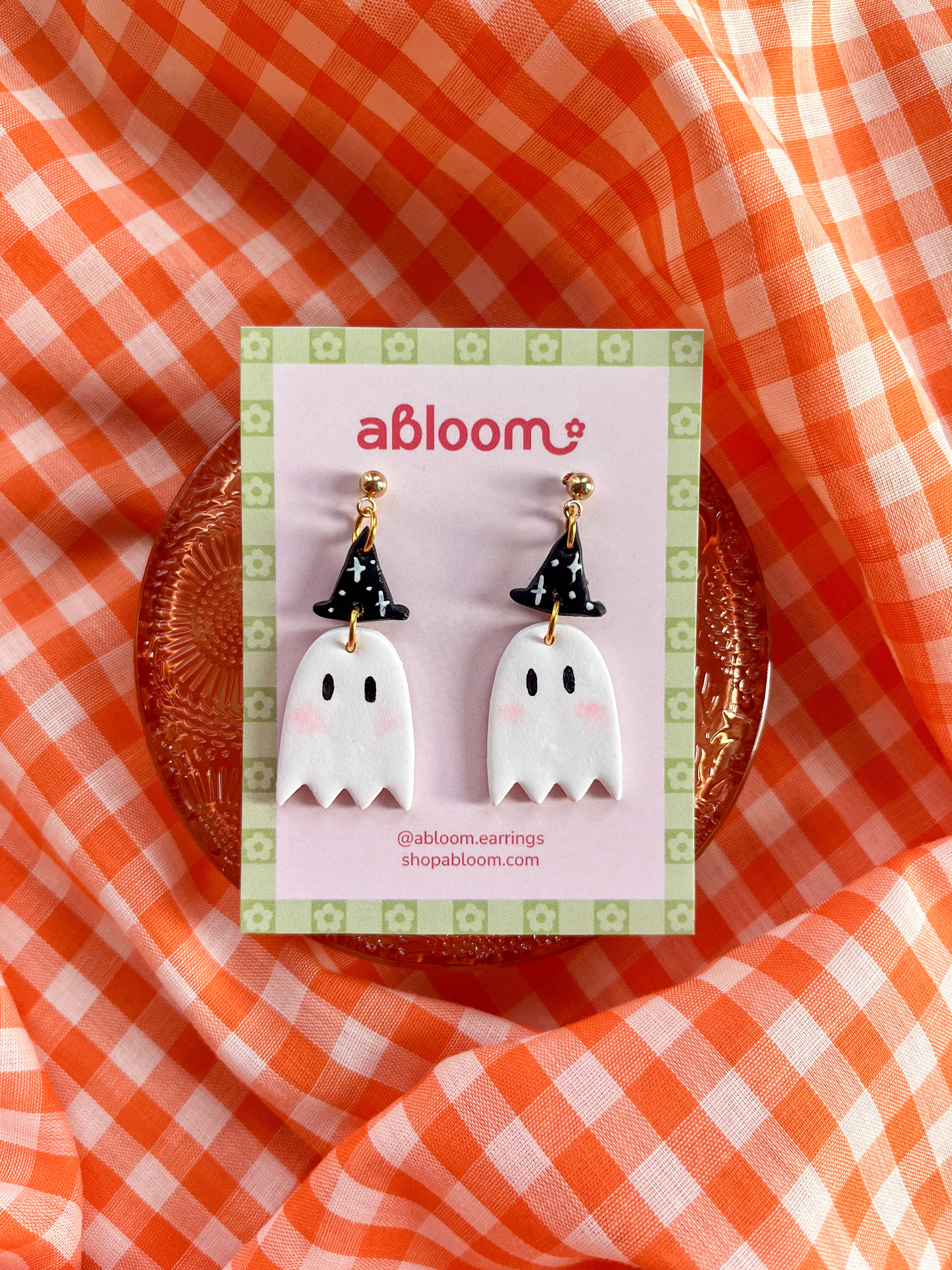 A pair of cute ghost drop earrings with black witch hats.