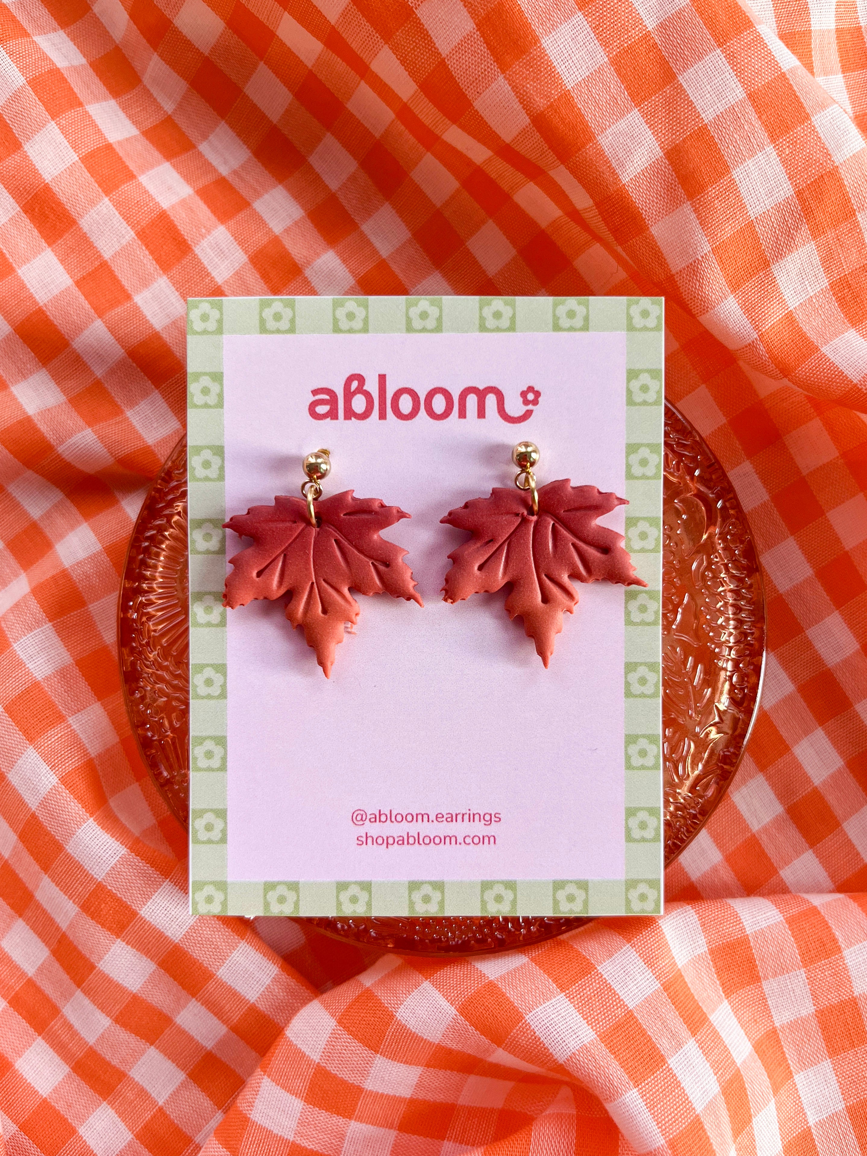 Maple Leaf-shaped dangle earrings in shades of red and orange.