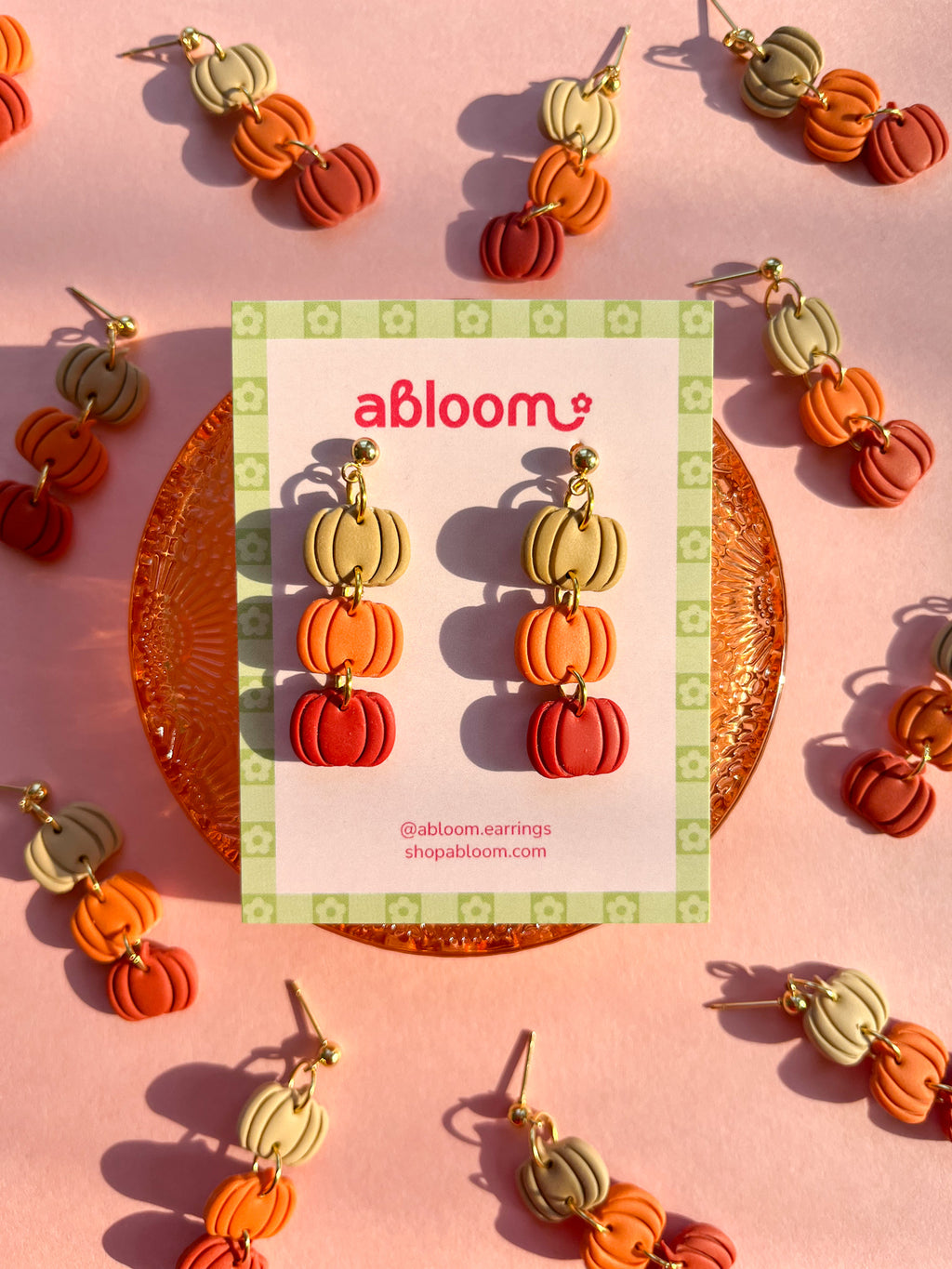 Pumpkin-shaped drop earrings in beige, orange, and red.