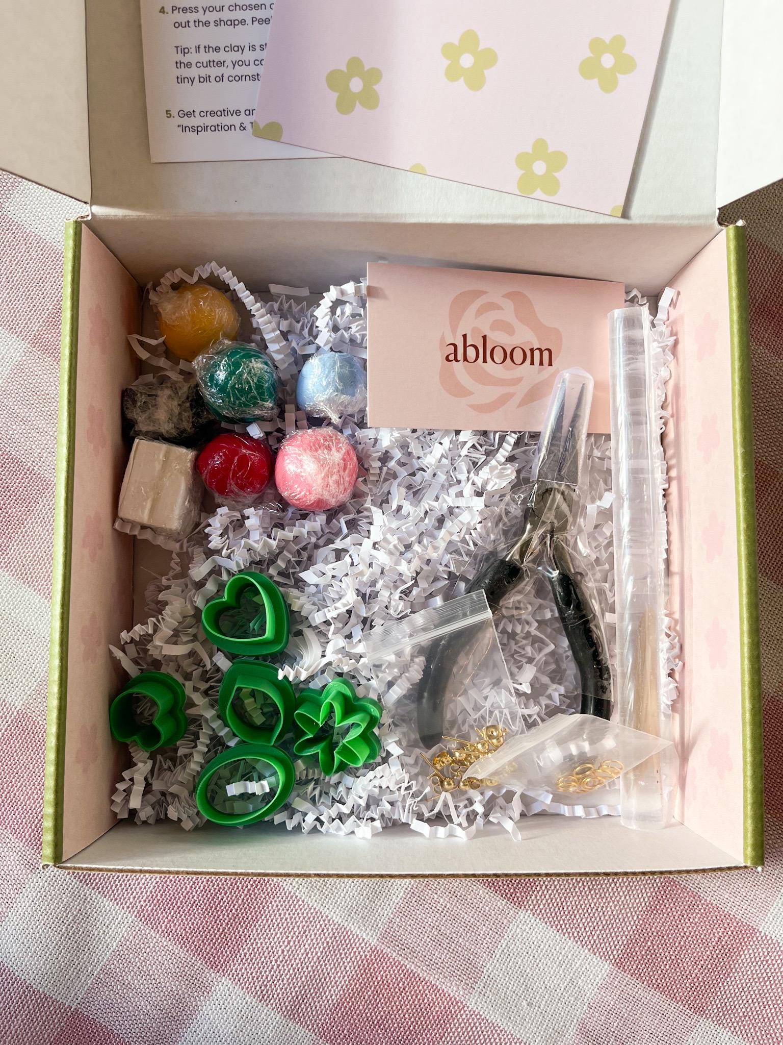 Gift box with 'abloom' branding containing clay cutters, pliers, clay, and findings. 