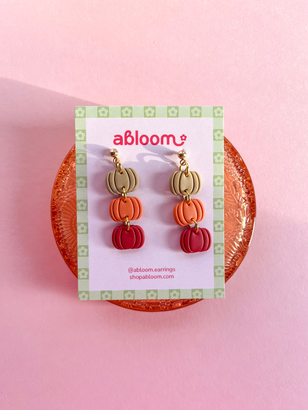 Pumpkin-shaped drop earrings in beige, orange, and red.