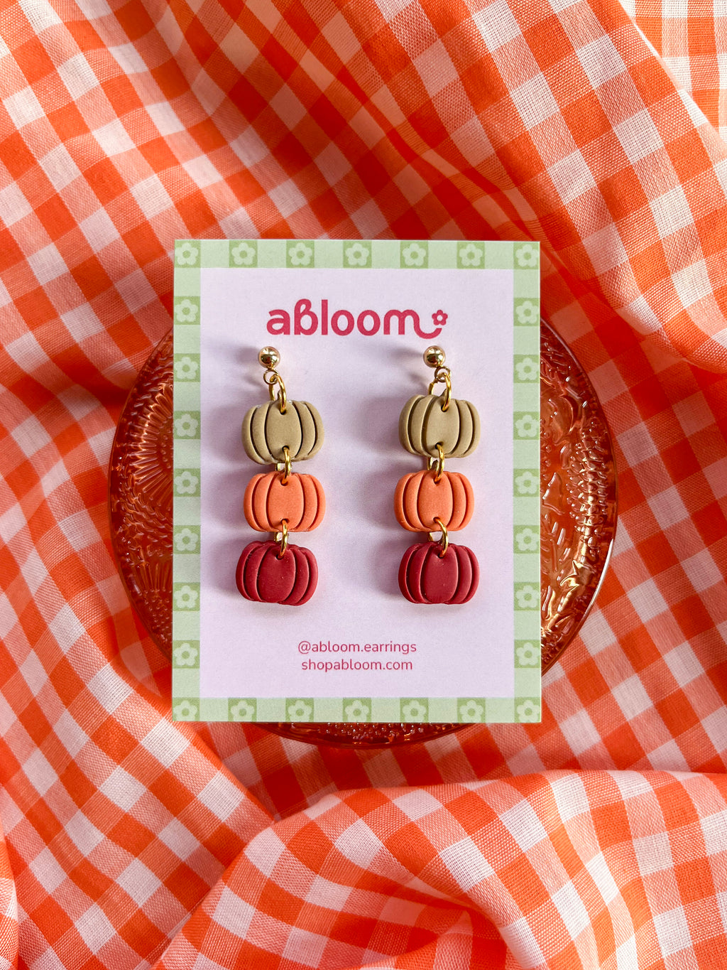 Pumpkin-shaped drop earrings in beige, orange, and red.