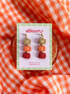 Pumpkin-shaped drop earrings in beige, orange, and red.