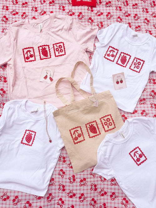 T-shirts and a tote bag with red and white designs on a red and white checkered background